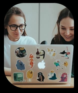 Two women smiling while looking at a laptop together